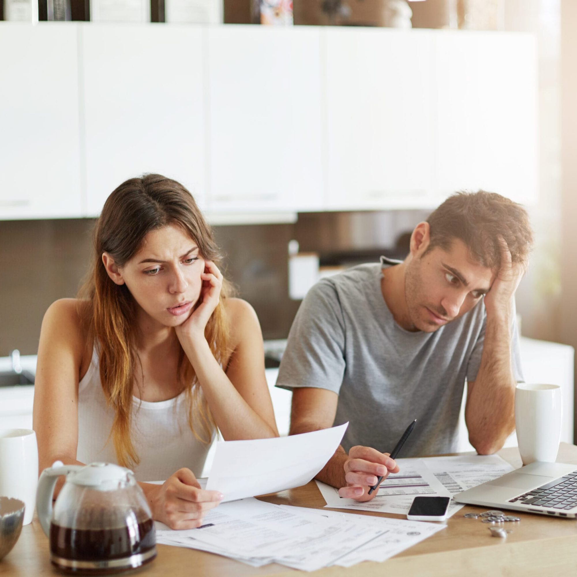 Unhappy couple being tired to work with documents. Young female helping her husband with managing finances, reading attentively documents, trying to find necessary figure. Family work concept Unhappy couple being tired to work with documents. Young female helping her husband with managing finances, reading attentively documents, trying to find necessary figure. Family work concept